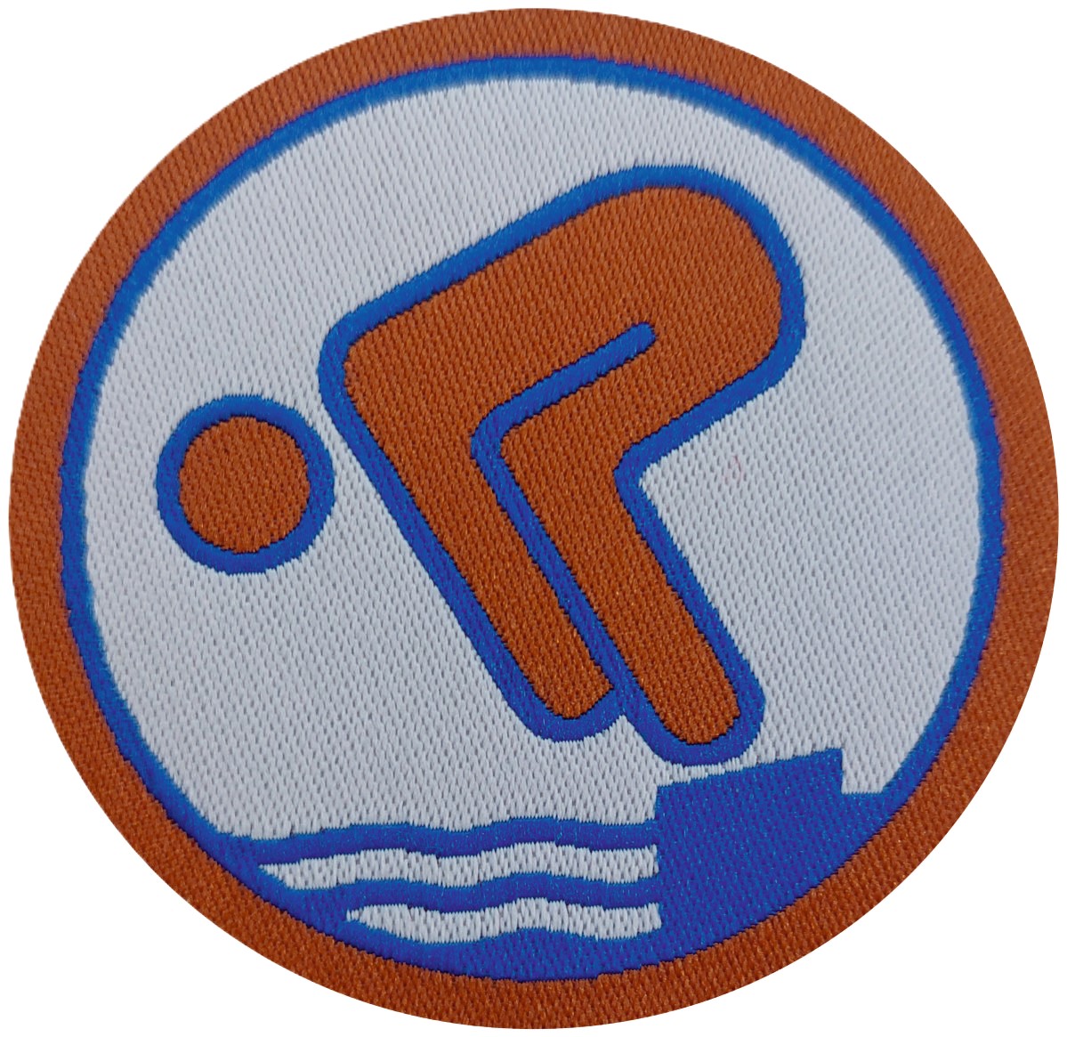 Runder Kreis mit bronze und blauer Umrandung. Im unteren Drittel sind 3 blaue Wellen und ein Block dargestellt. Darauf ist ein menschliches Piktogramm in bronze und blauer Umrandung der zum Sprung ansetzt.